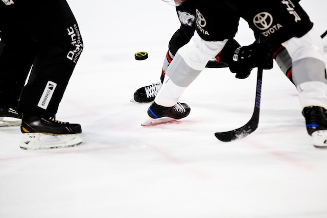 2 hockey players and refferey standing near to puck